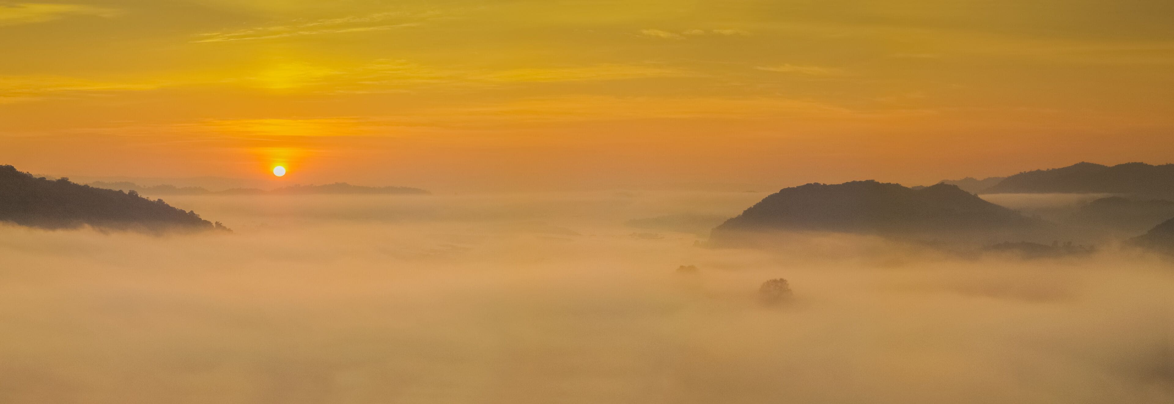 sunrise at Phu Huay Esan View Point, view of the hill around with sea of mist above Mekong river with yellow sun light in the sky background, Ban Muang, Sang Khom District, Nong Khai, Thailand.