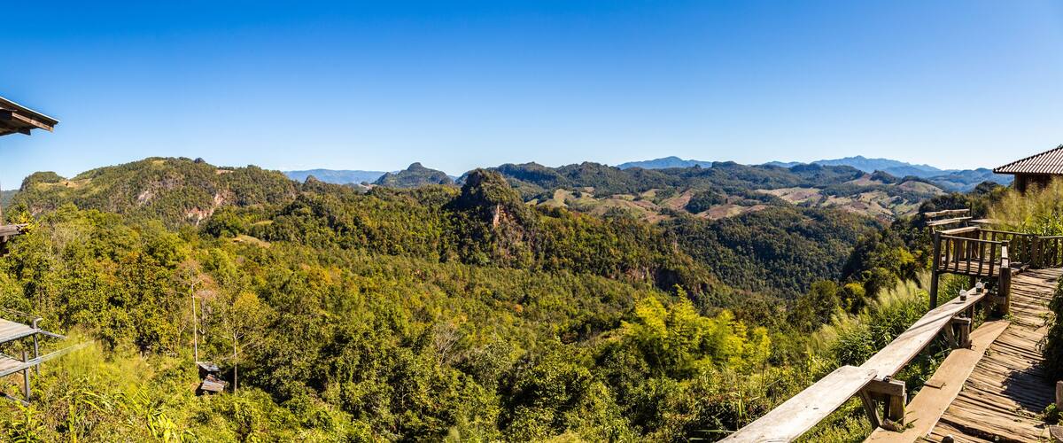 A wooden observation deck overlooking a forested valley with distant mountains.