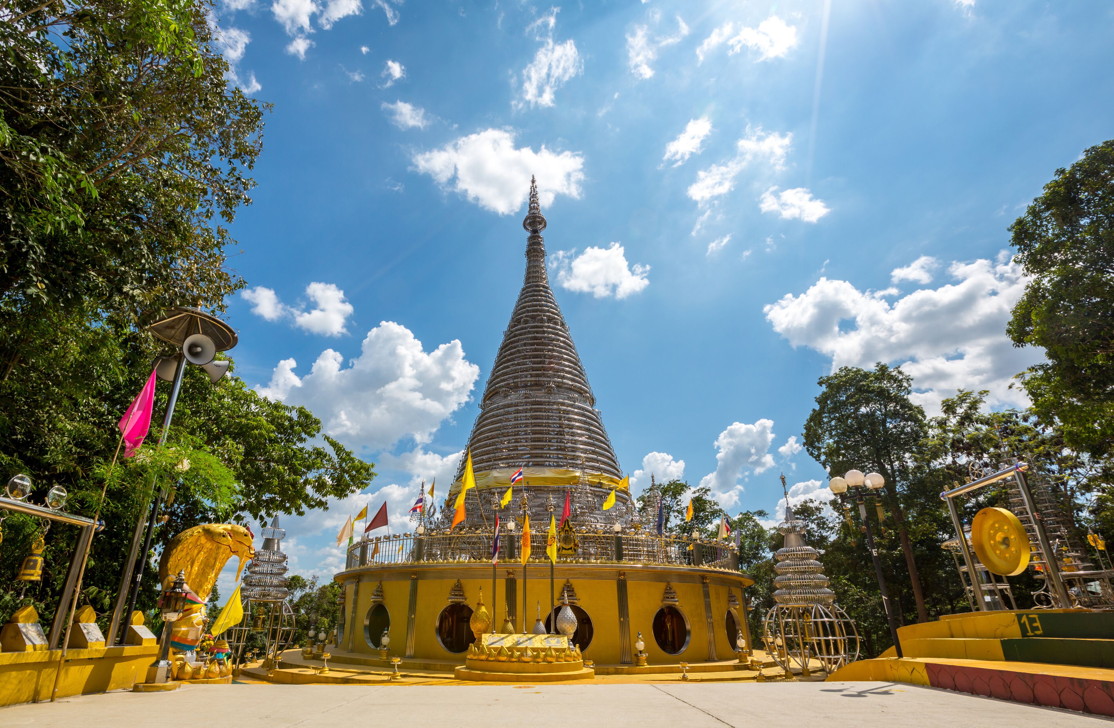 A large stupa surrounded by flags and golden statues.
