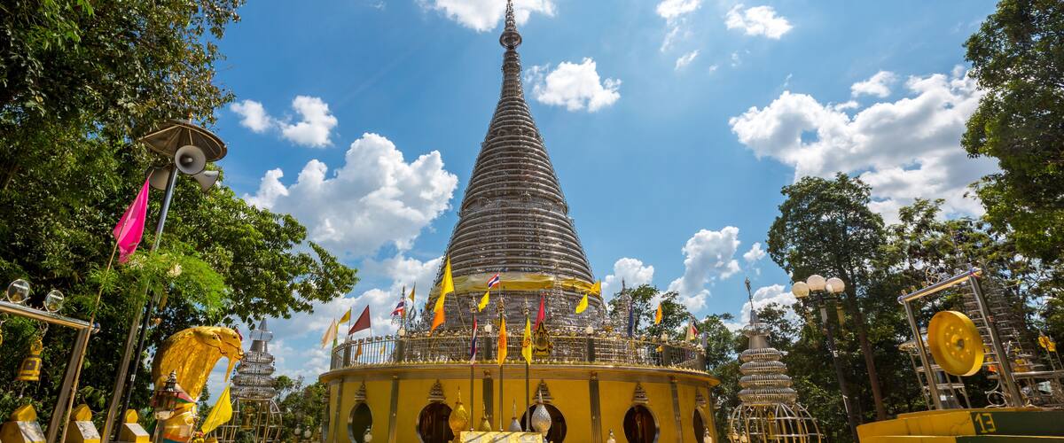 A large stupa surrounded by flags and golden statues.