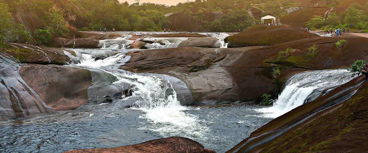 A waterfall cascading over rocks in a forested area with a viewing platform.