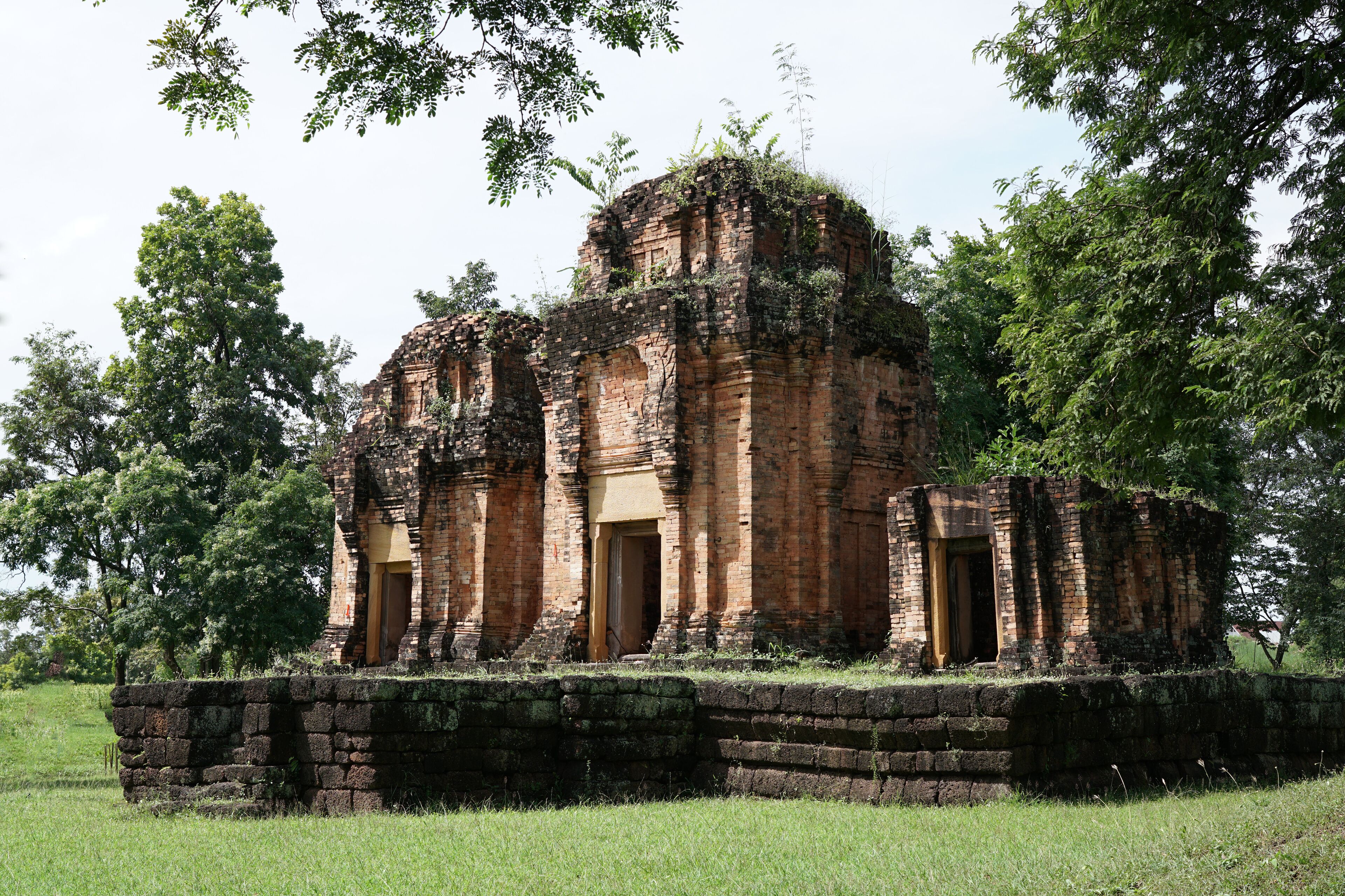 An ancient brick temple surrounded by lush greenery.