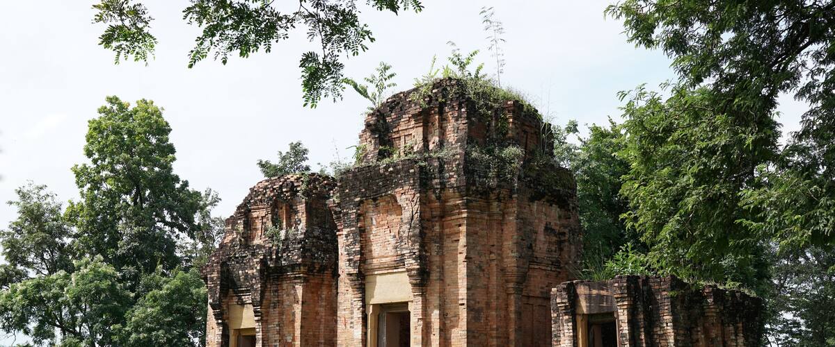An ancient brick temple surrounded by lush greenery.