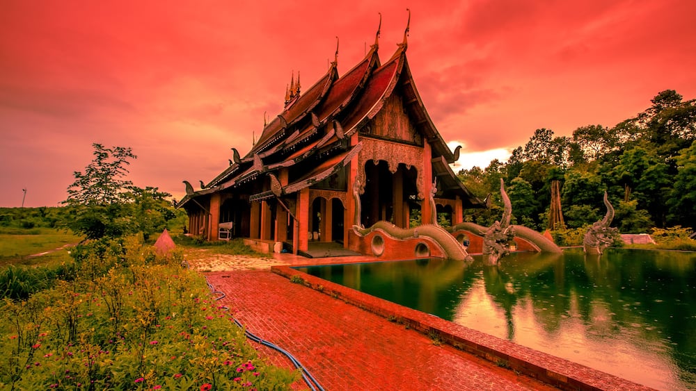 The background of the Wat Pa Kham Charoen is a beautiful old church with a Buddhist statue and a tree-lined temple, with tourists and travelers always making merit in Udon Thani, Thailand.