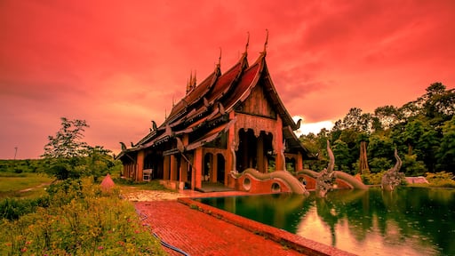The background of the Wat Pa Kham Charoen is a beautiful old church with a Buddhist statue and a tree-lined temple, with tourists and travelers always making merit in Udon Thani, Thailand.