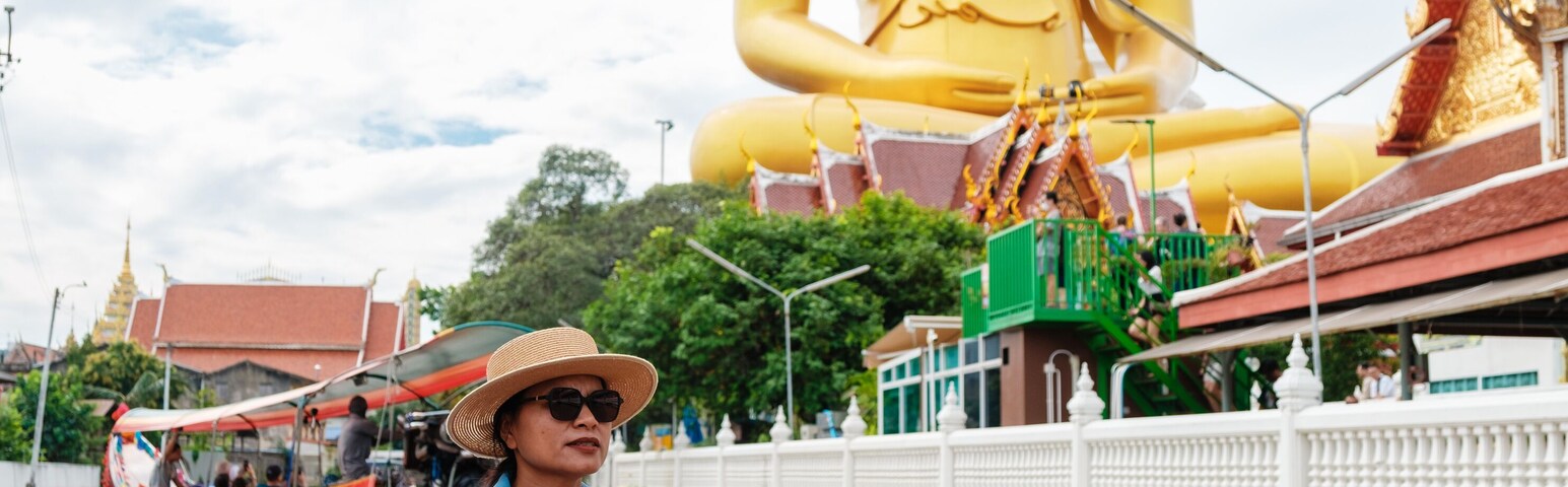 Una persona en un bote, con una gran estatua dorada de Buda al fondo.