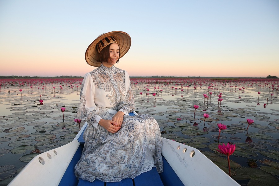 Beautiful woman, fashion girl in hat and lake with red lotuses in Udon Thani, Thailand. Nong Han Kumphawapi Lake or Red Lotus Lake (Talay Bua Daeng). Pink flowers, Thai nature, landmark. Thai scenery