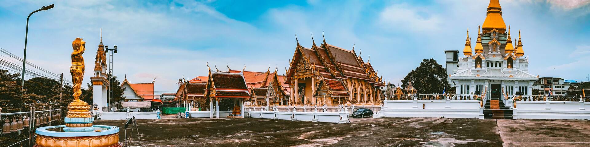 A temple complex with ornate architecture, including a prominent golden spire and traditional Thai buildings.