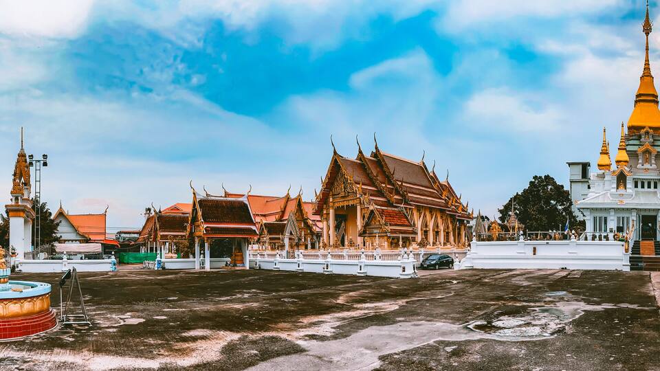 A temple complex with ornate architecture, including a prominent golden spire and traditional Thai buildings.