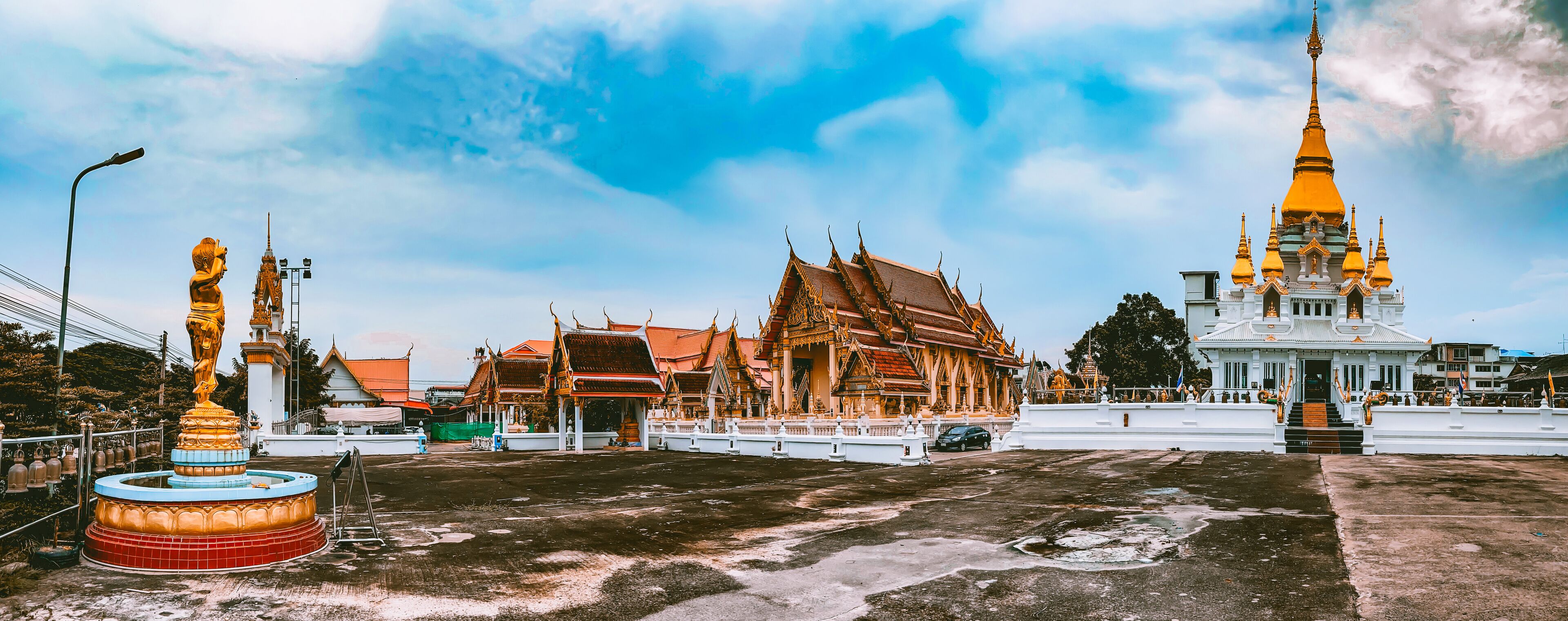 A temple complex with ornate architecture, including a prominent golden spire and traditional Thai buildings.