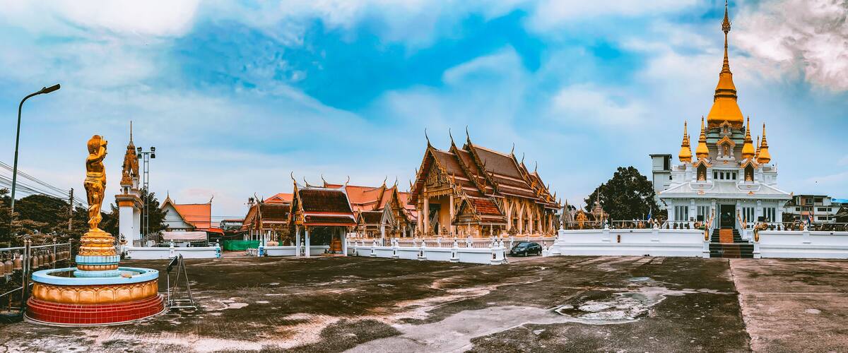 A temple complex with ornate architecture, including a prominent golden spire and traditional Thai buildings.