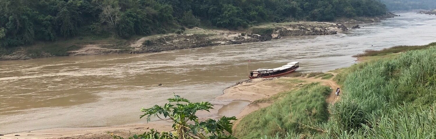 A river with a boat, surrounded by lush greenery and hills.