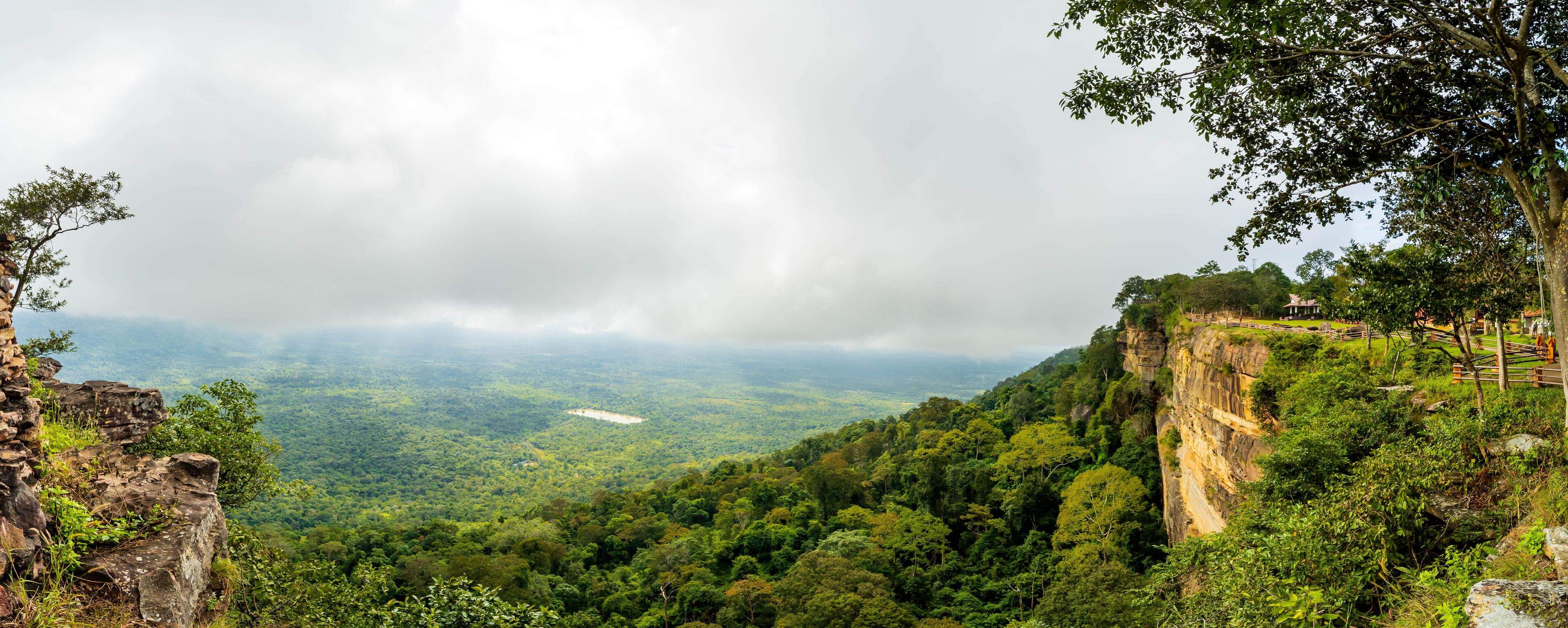 A lush green valley with a stone structure on a cliff edge.