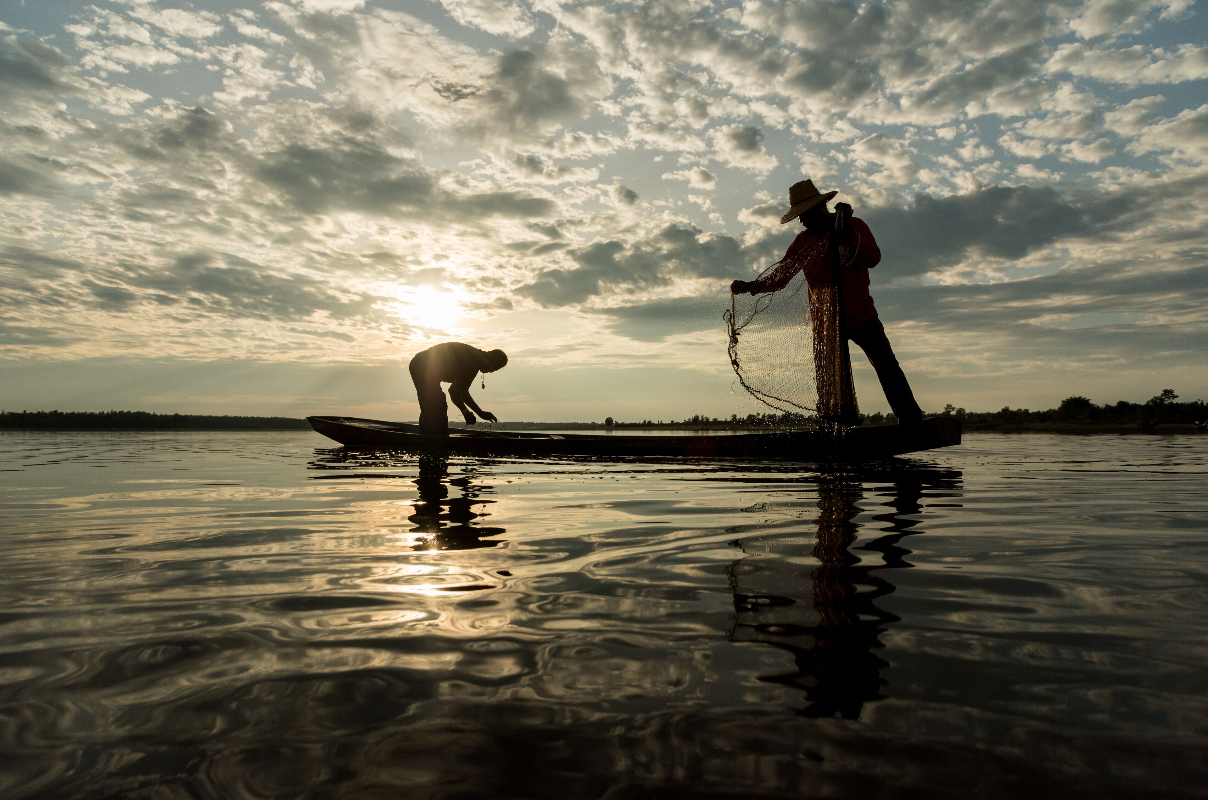Silhouette of Fishermen throwing net fishing in sunset time at Wanon Niwat district Sakon Nakhon Northeast Thailand.