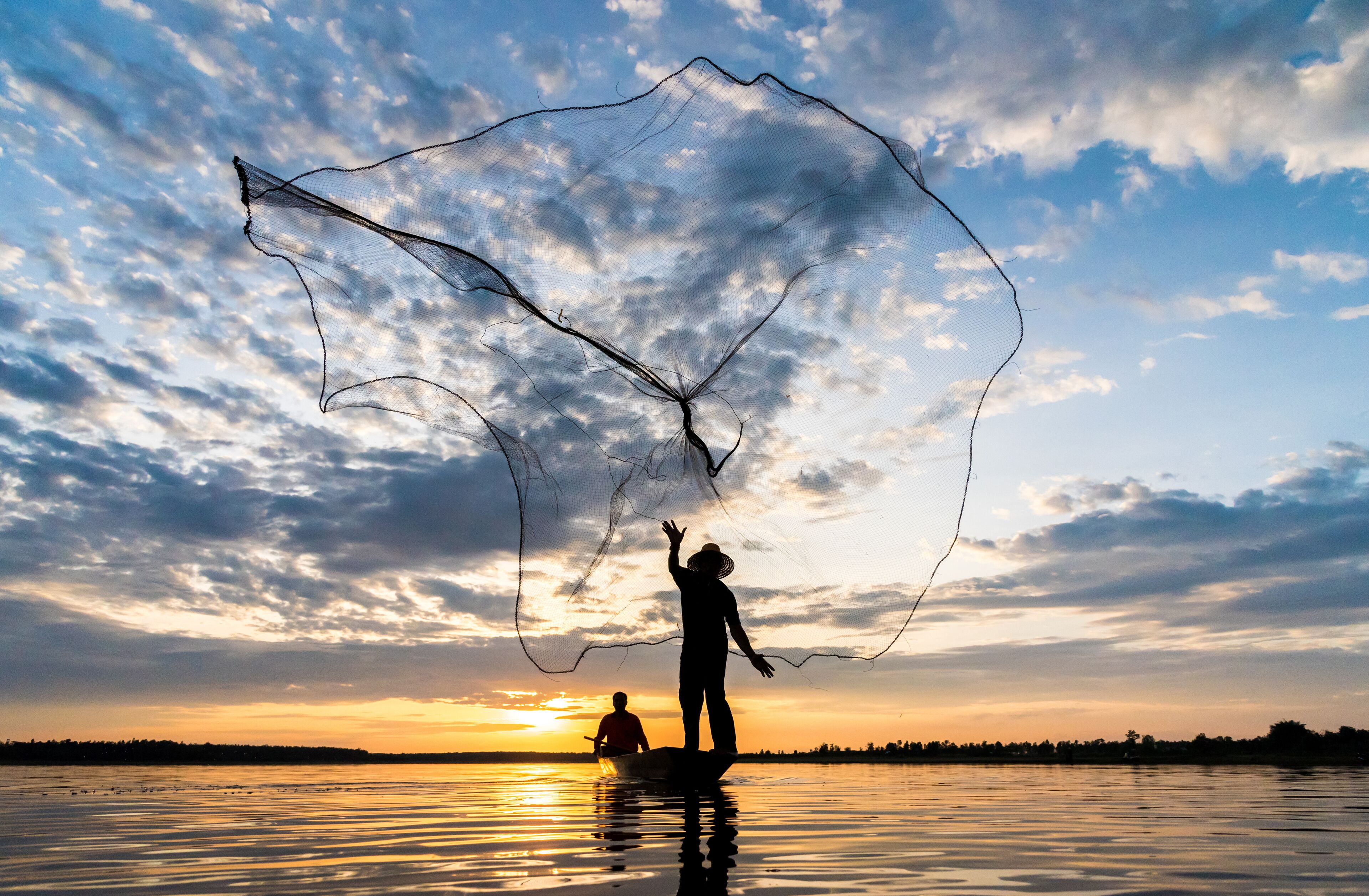 Silhouette of Fishermen throwing net fishing in sunset time at Wanon Niwat district Sakon Nakhon Northeast Thailand.