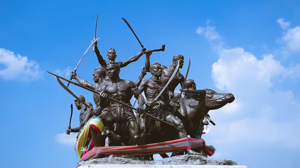 A bronze statue of warriors on horseback, set against a clear blue sky.