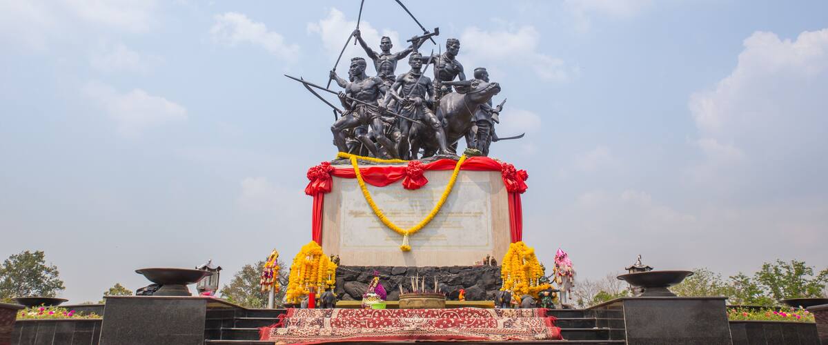 A statue of soldiers on horseback with a banner and garlands.