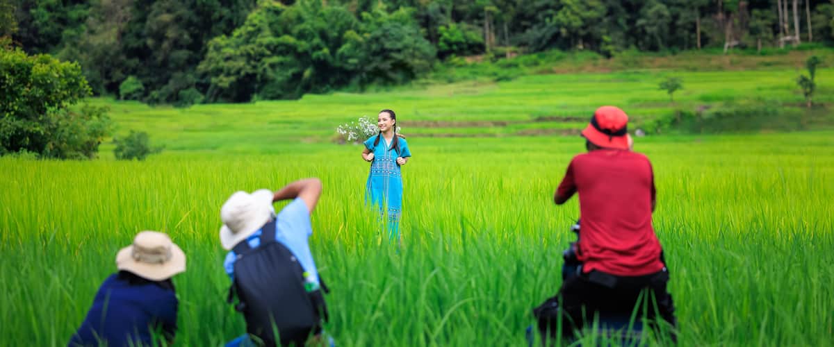A person in a blue dress standing in a lush green field with three people in the foreground.