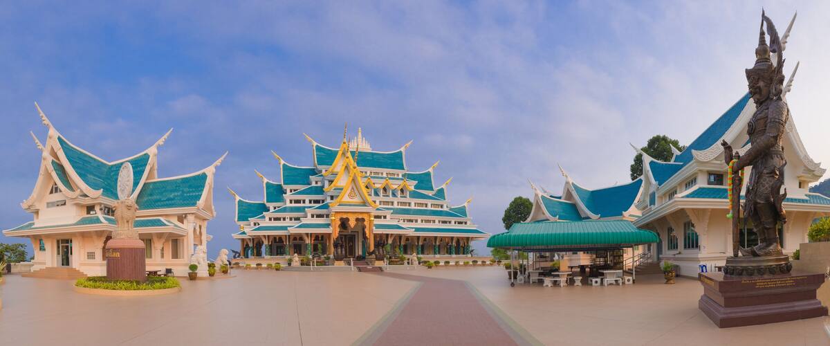 A traditional Thai temple complex with ornate architecture and statues.
