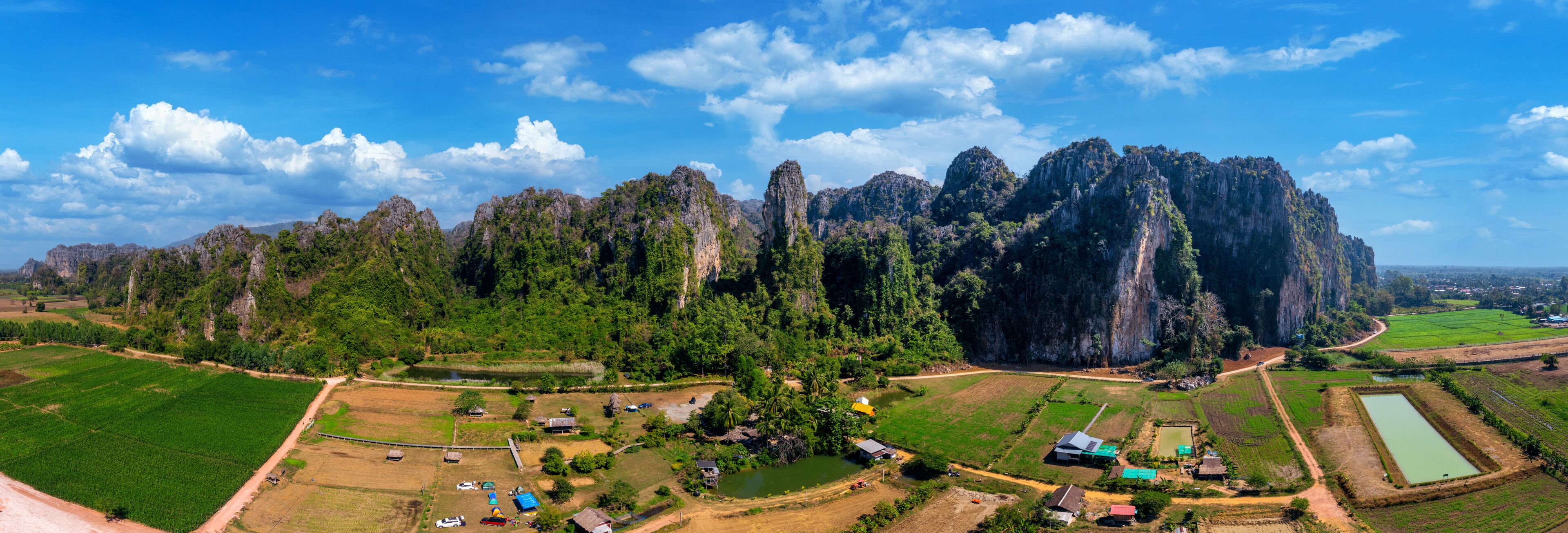 A rural landscape with terraced fields, a small village, and limestone karst mountains.