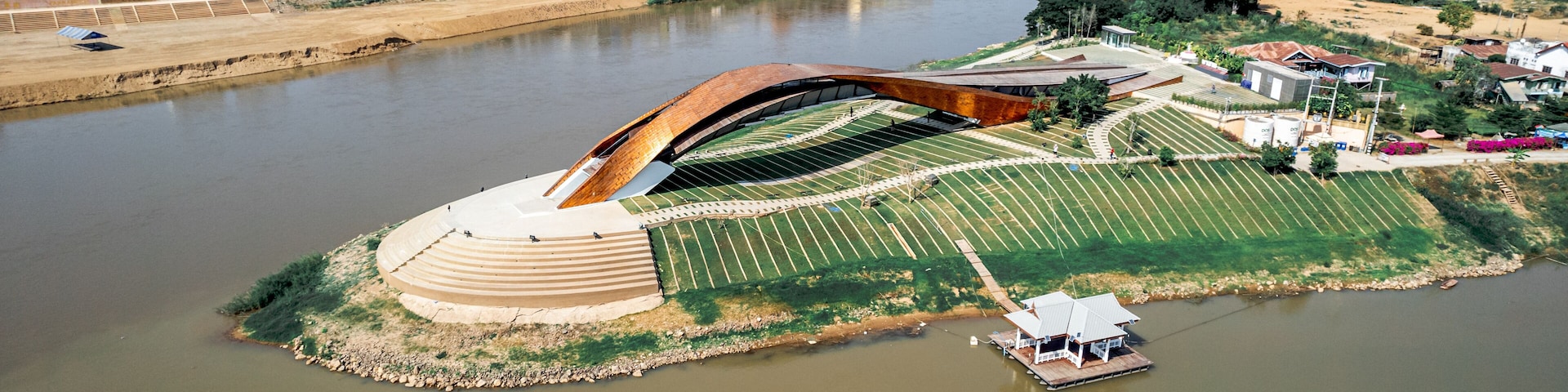 Un puente moderno sobre un río, rodeado de edificios urbanos y vegetación.