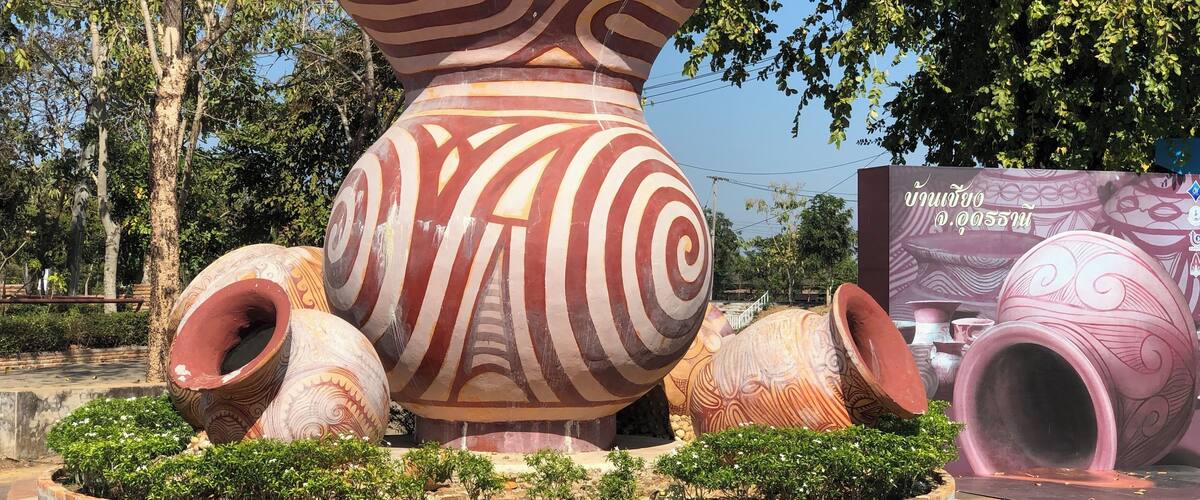 A large decorative pottery installation with intricate patterns, surrounded by a circular water feature and greenery.