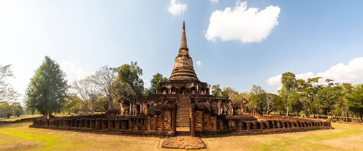 An ancient temple with a tall spire, surrounded by trees and a clear sky.