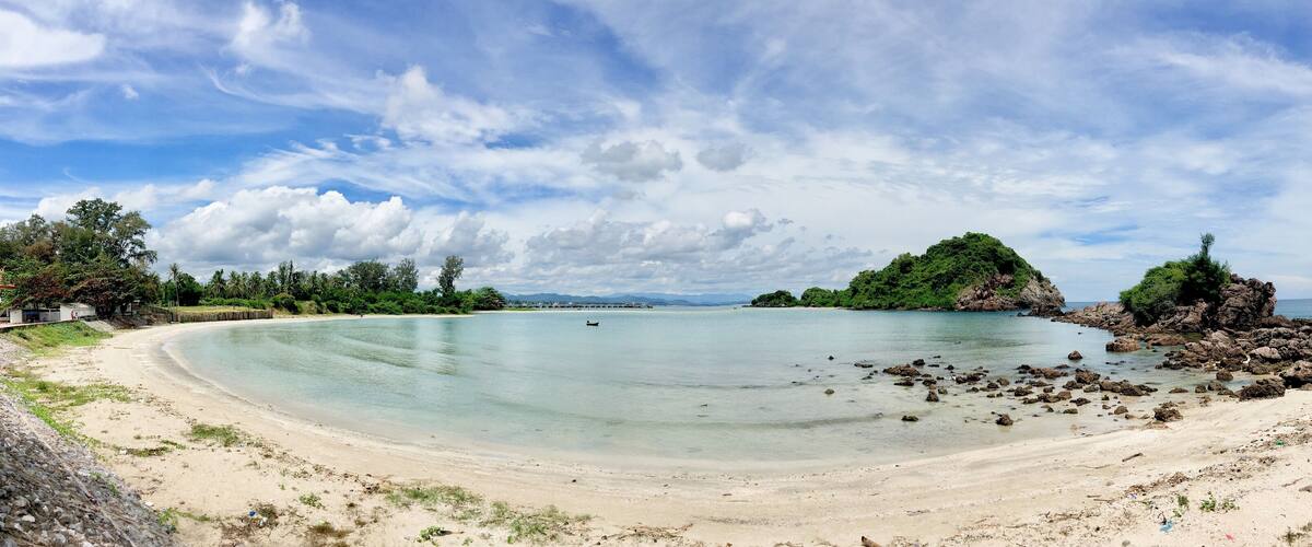 A beach with clear turquoise water, a sandy shore, and rocky outcrops.