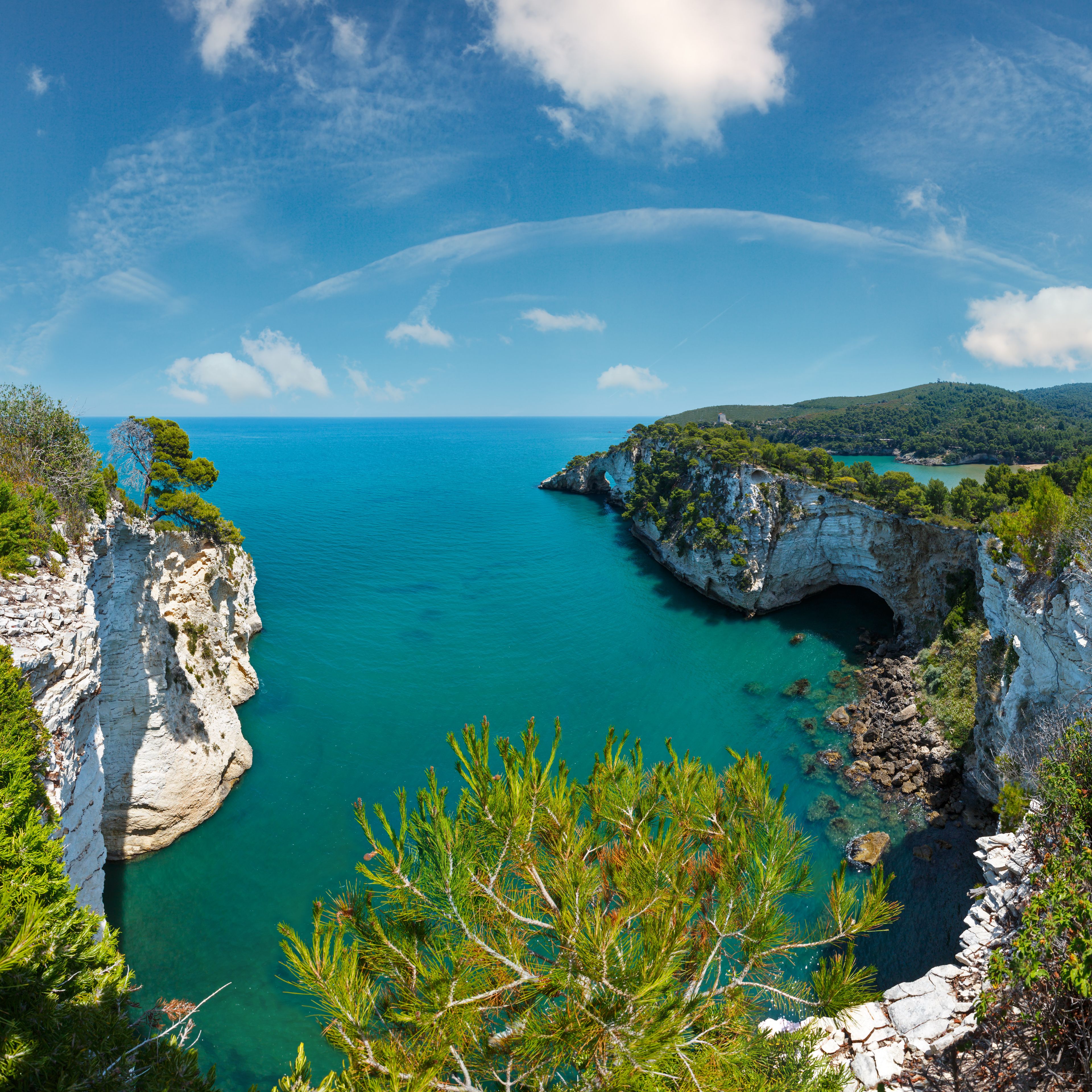 Un paysage côtier avec des falaises, une mer turquoise et un ciel dégagé.