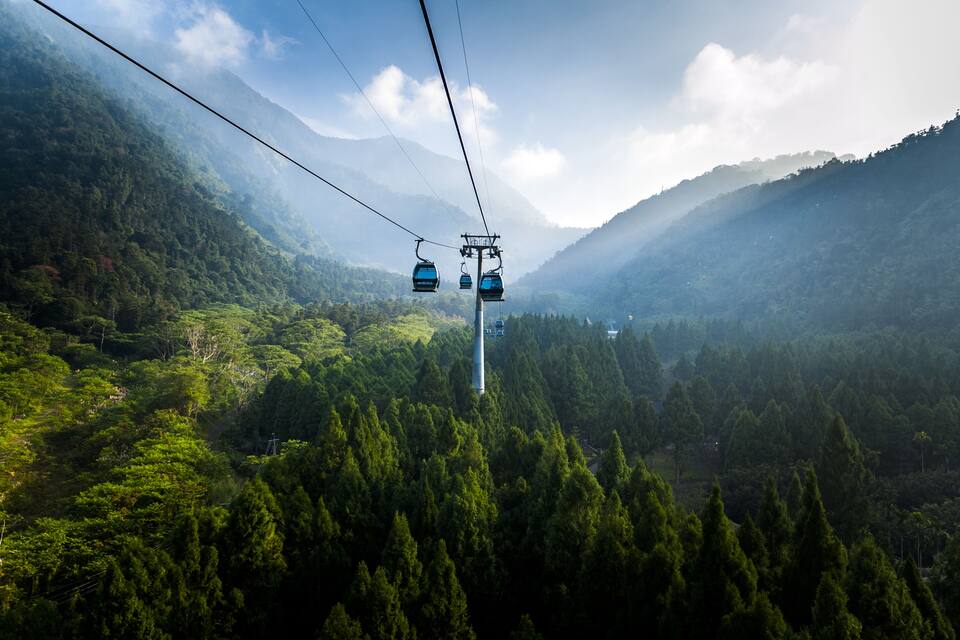 A cable car system in a mountainous area with dense forests.