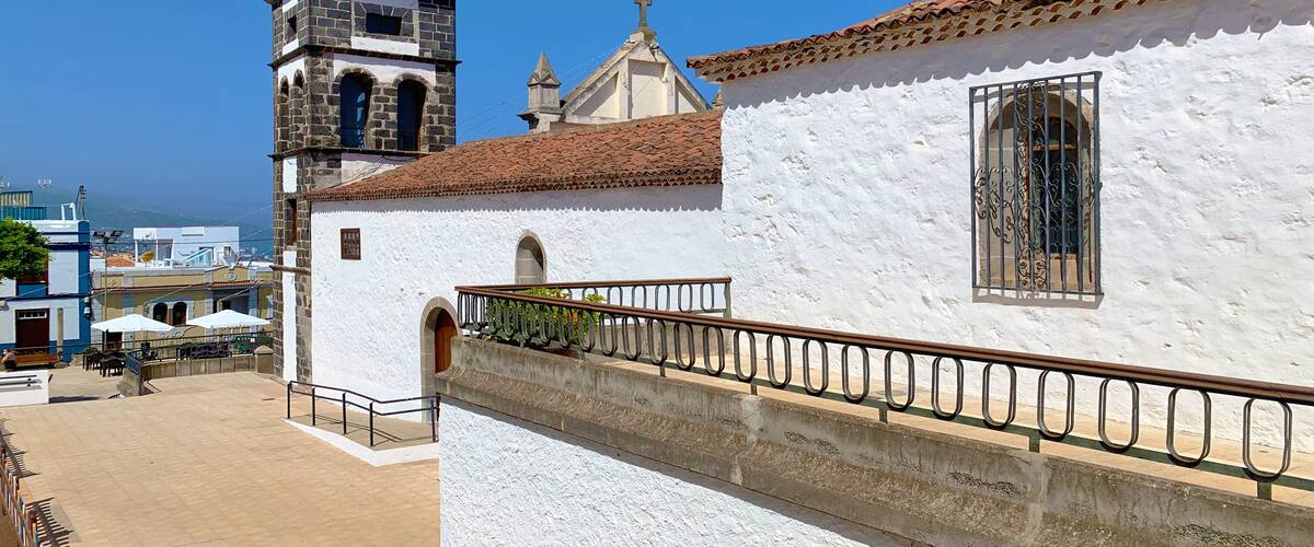 A church with a tall bell tower and a white building with a tiled roof.