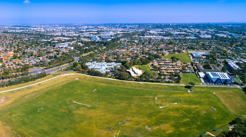 An aerial view of a densely populated urban area with residential neighborhoods, a large green park, and industrial buildings.