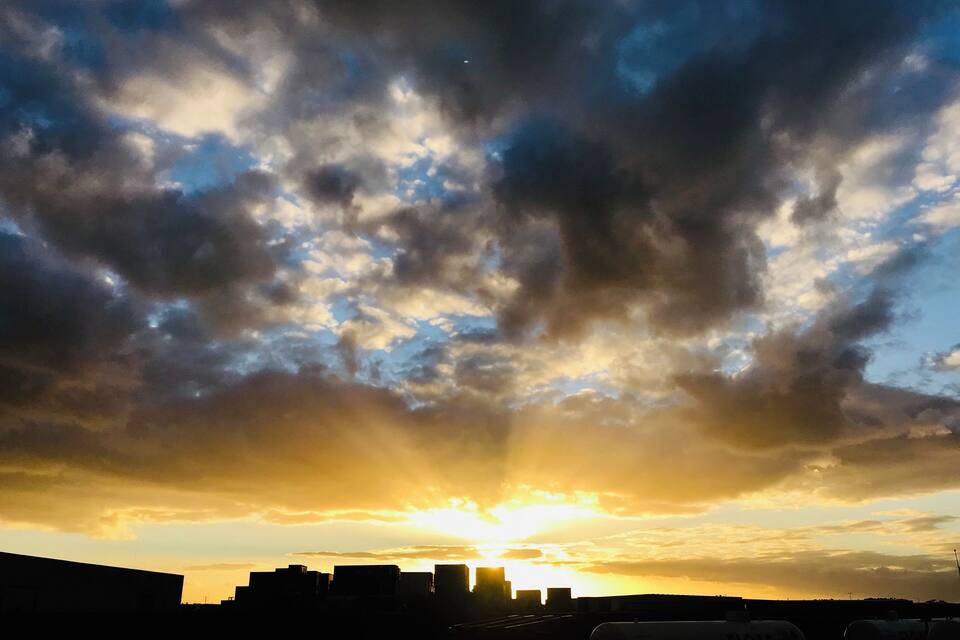 A sunset over a city skyline with clouds.