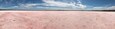 Eine weite, rosa Salzwüste unter blauem Himmel.