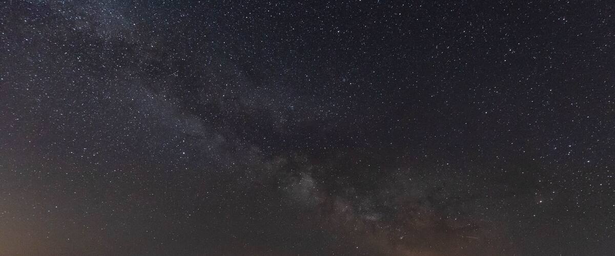 A night sky filled with stars over a rocky coastline.