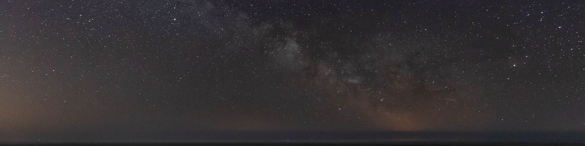 A night sky filled with stars over a rocky coastline.