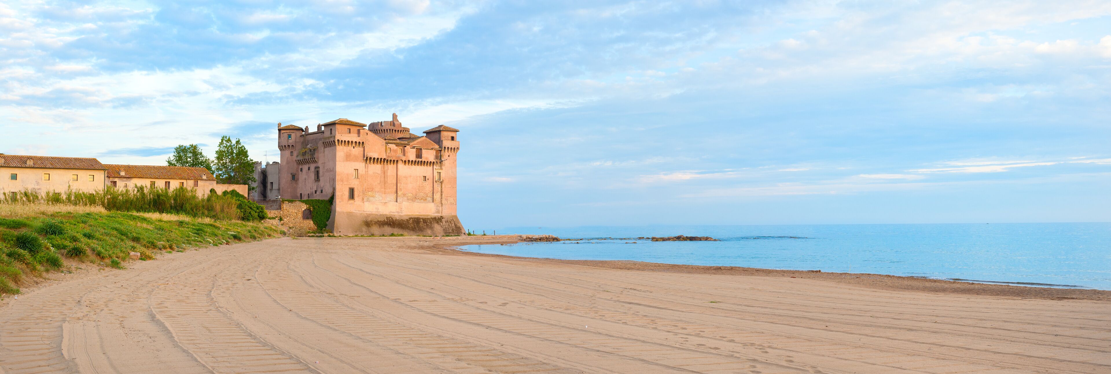 A castle by the sea with a sandy path leading to it.