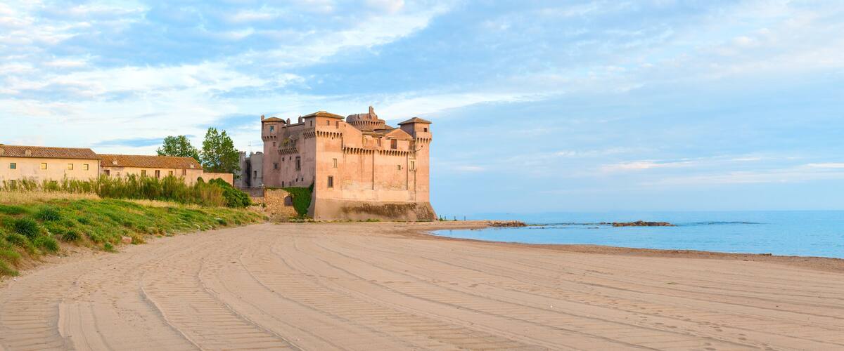 A castle by the sea with a sandy path leading to it.