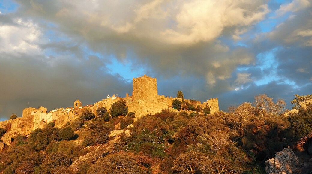 A castle atop a hill with a rainbow in the sky.