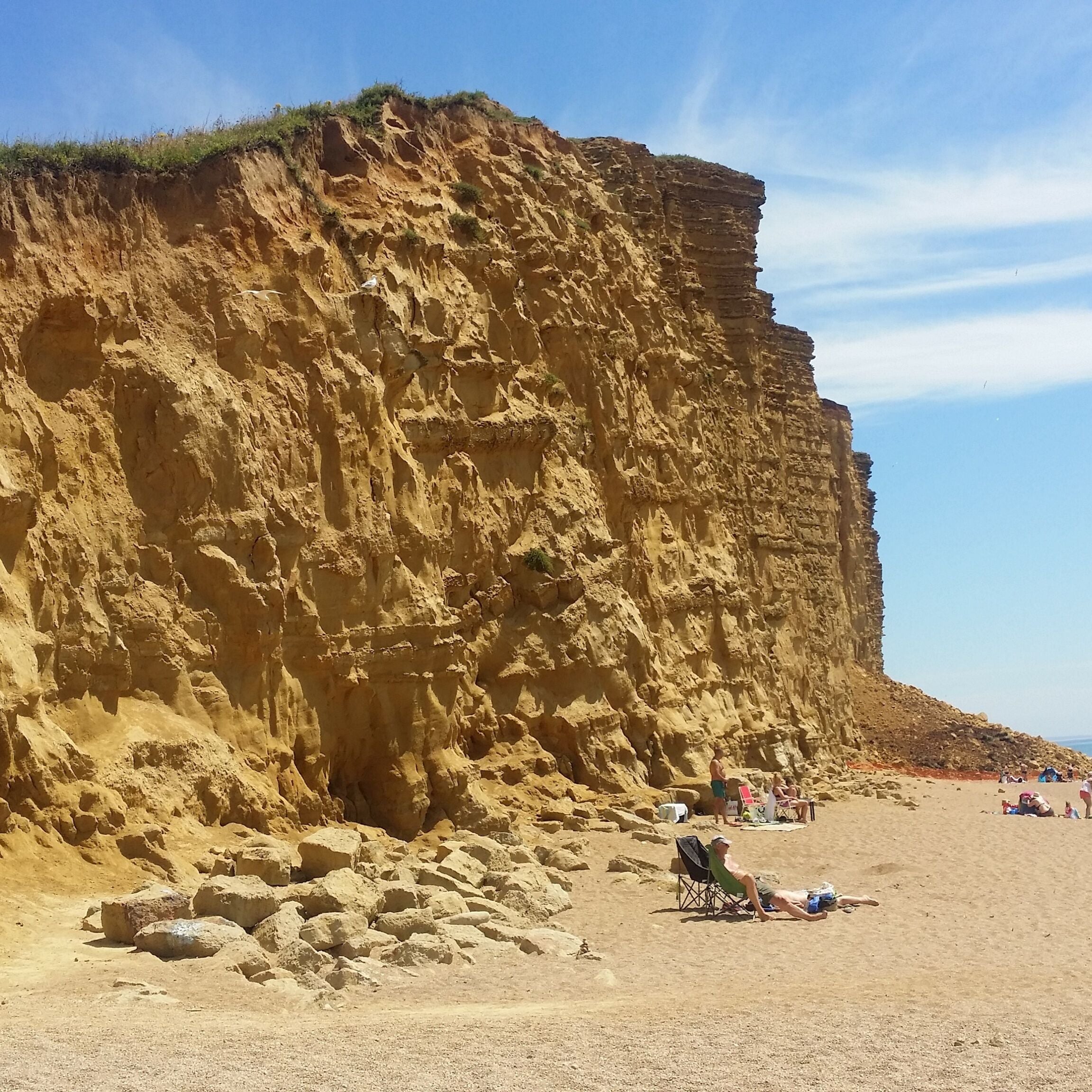 A sandy beach with a large cliff.