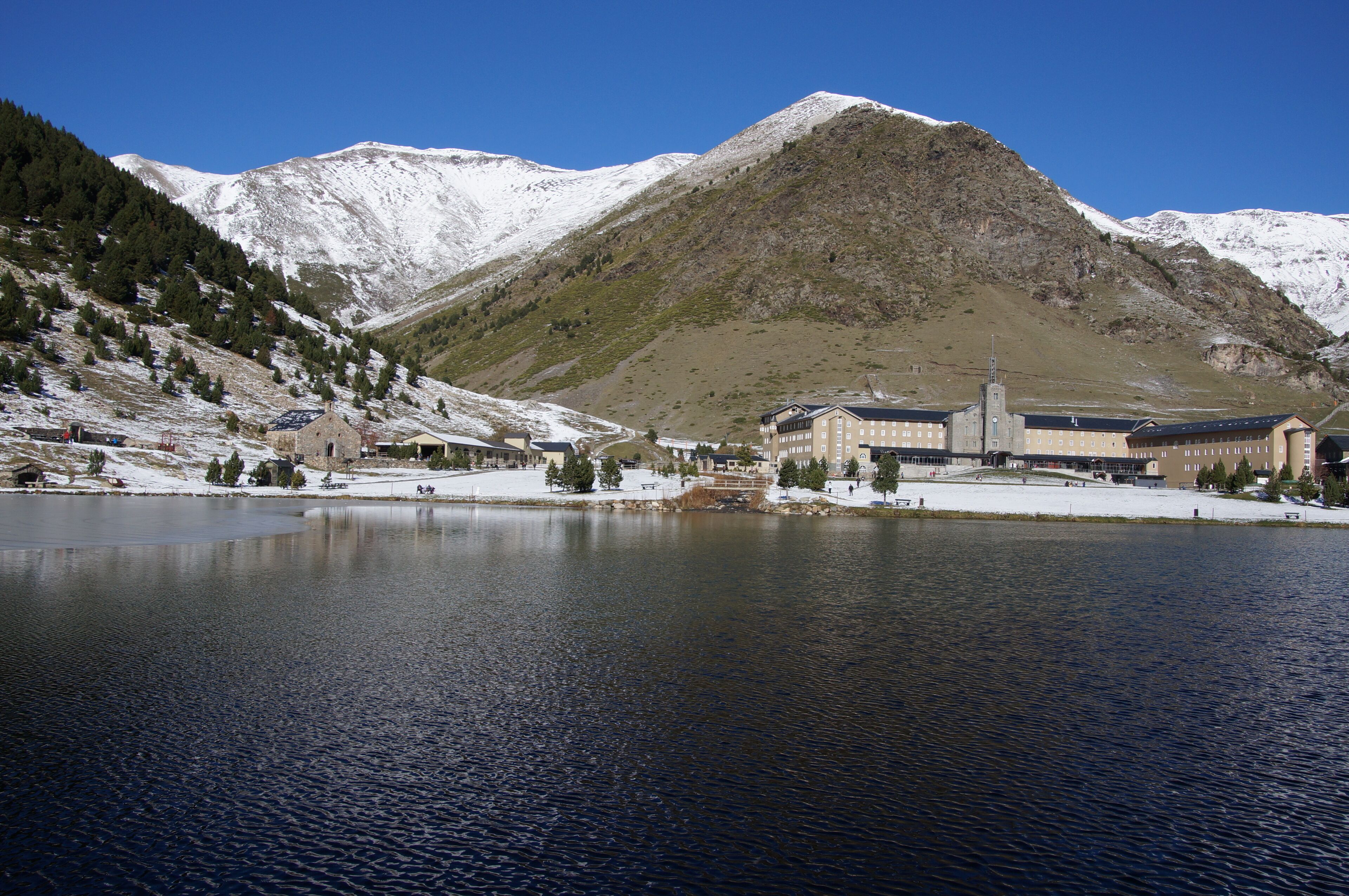 A mountainous landscape with a large building near a lake.