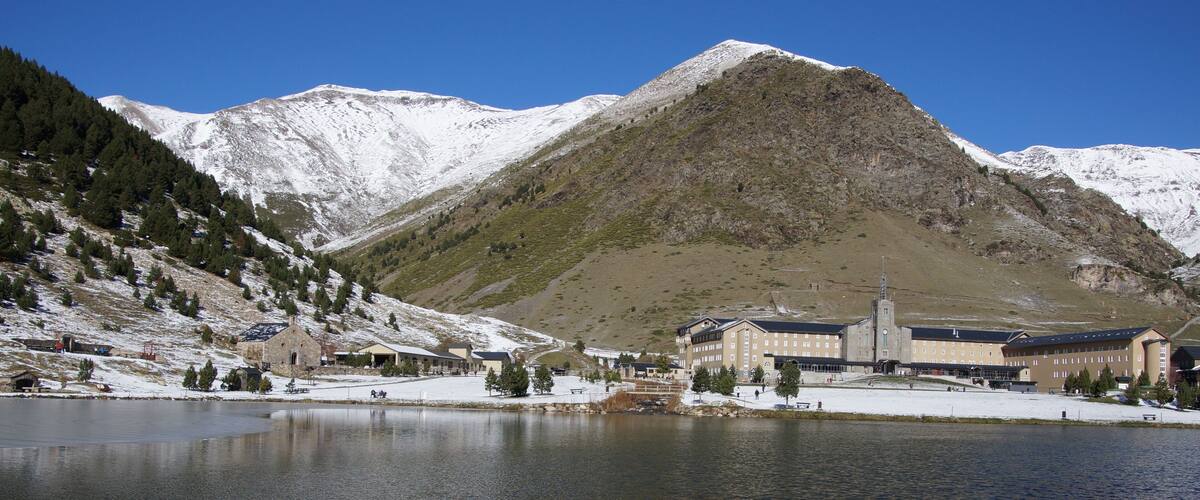 A mountainous landscape with a large building near a lake.