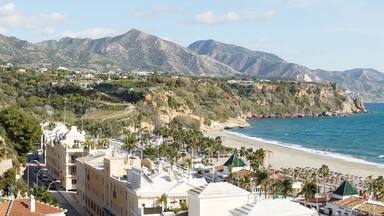 Un pueblo costero con playa, montañas y edificios.