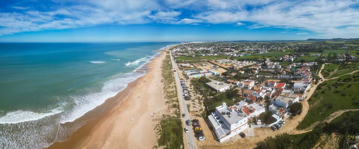 A coastal town with a beach, houses, and a clear sky.
