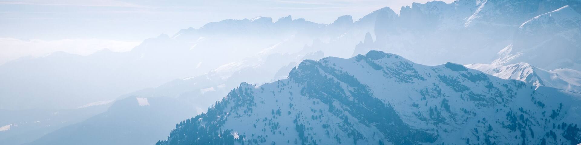 Banner with Morning mountain landscape at a ski resort Campitello di Fassa Italy. Sun and haze in the mountains