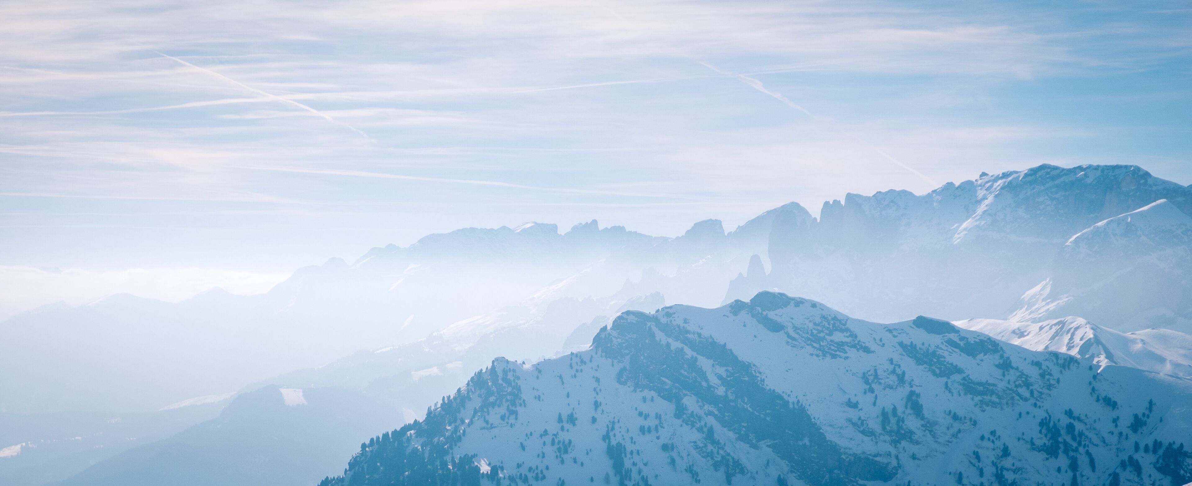 A snow-covered mountain range with clear skies and distant peaks.