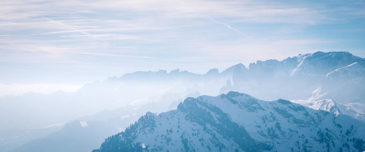 A snow-covered mountain range with clear skies and distant peaks.