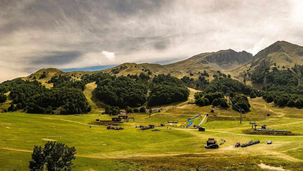 A mountainous landscape with a green field, a ski lift, and a small building.