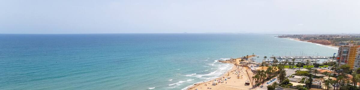 Cropped image panoramic view Mediterranean Sea and coastline with sandy beach of Dehesa de Campoamor, clear blue sky copyspace for text. Travel, summer holidays concept. Spain, Costa Blanca, Alicante