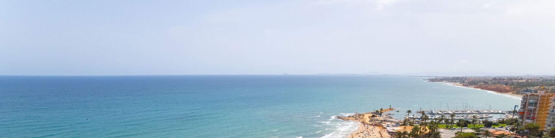Cropped image panoramic view Mediterranean Sea and coastline with sandy beach of Dehesa de Campoamor, clear blue sky copyspace for text. Travel, summer holidays concept. Spain, Costa Blanca, Alicante